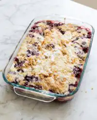 A rustic Blackberry Dump Cake with Butter Pecan Cake Mix cooling on a farmhouse table.