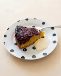 A rustic Blackberry Upside Down Cake cooling on a wooden table with fresh berries.