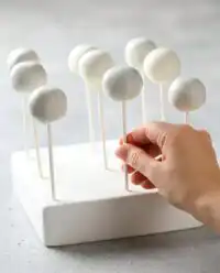A pile of rustic Oreo Cake Pops drizzled with chocolate on a farmhouse plate