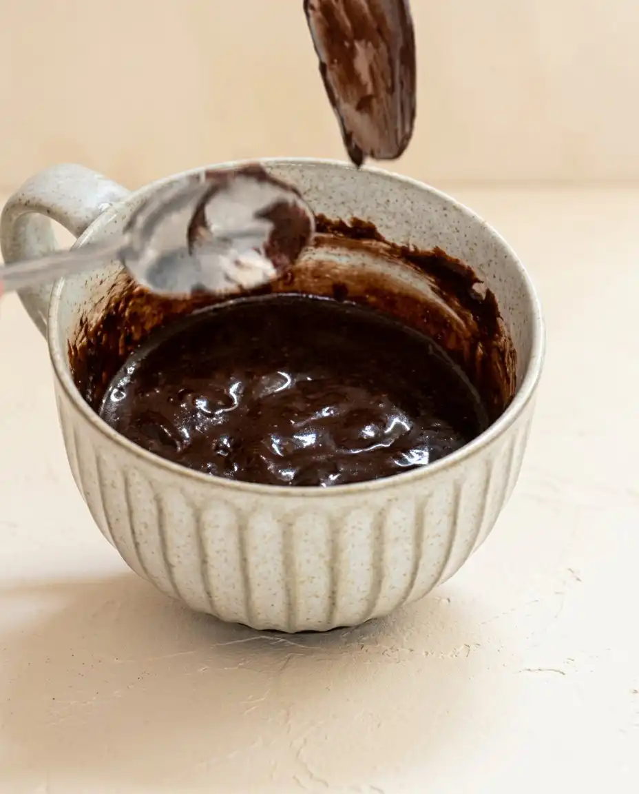 Pantry ingredients for a Chocolate Mug Cake measured out in small enamel bowls on a wooden counter.