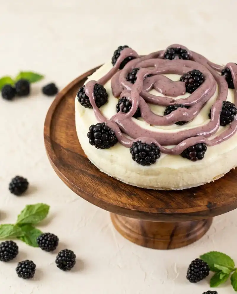 A beautiful slice of layered Blackberry Vanilla Cake with deep purple curd on an antique porcelain plate.