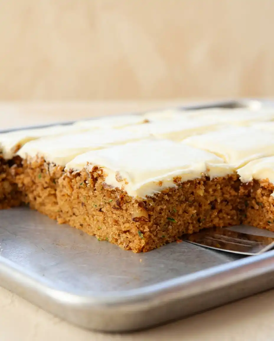 Zucchini Spice Cake 16 A clean slice of frosted Zucchini Spice Cake served on a white plate with a fork nearby