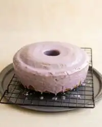 A golden Southern Blackberry Pound Cake drizzled with lavender glaze on a vintage platter.