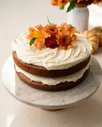 A golden brown butter pumpkin cake on a vintage pedestal stand with warm autumn spices.