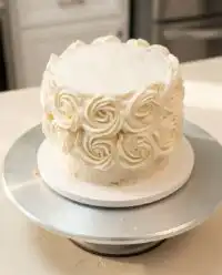 A gorgeous White Velvet Cake frosted with silky ermine icing sits on a classic glass cake stand.