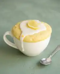 A warm and fluffy Lemon Mug Cake in a white coffee mug fresh from the microwave.