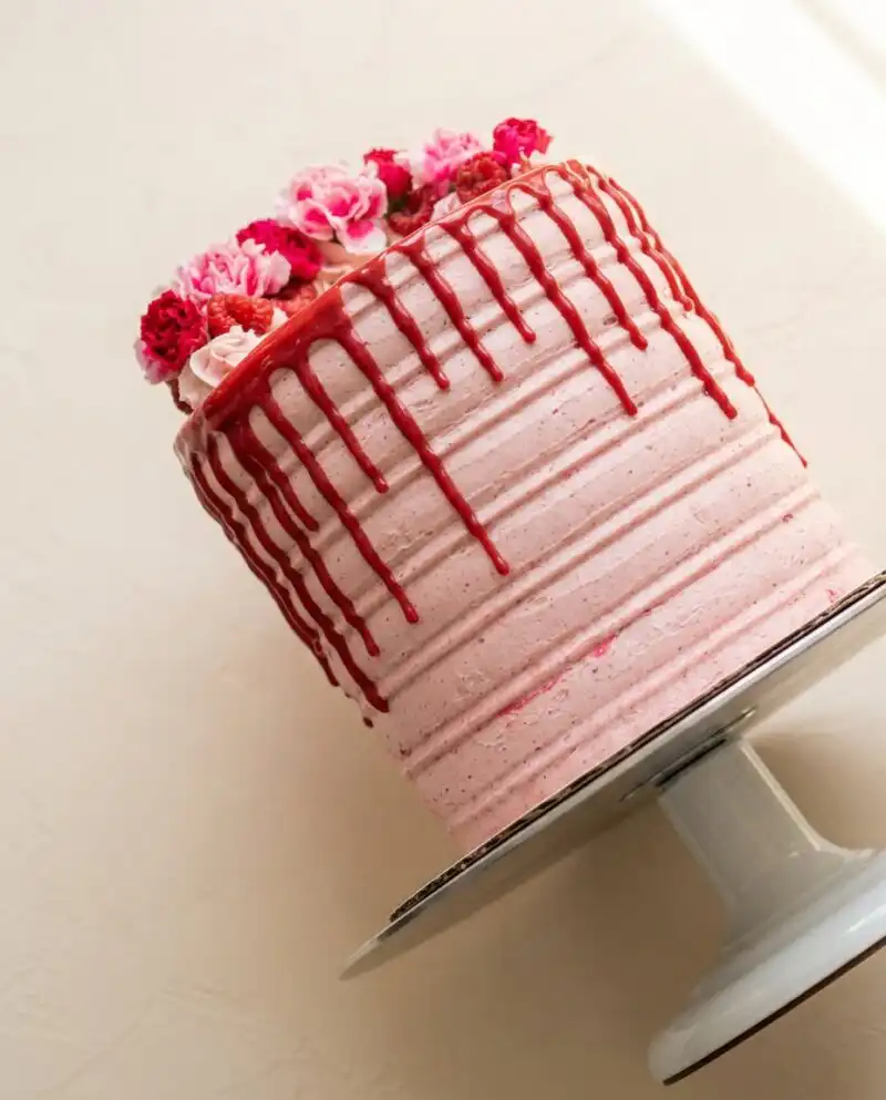A beautiful rustic White Chocolate Raspberry Anniversary Cake on a ceramic pedestal.